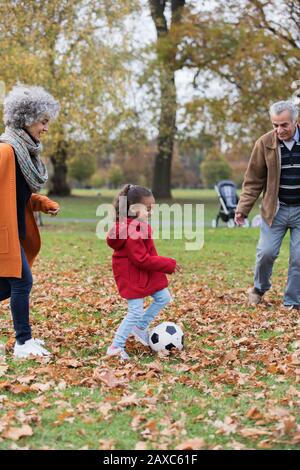 Großeltern spielen mit Enkelin im Herbstpark Fußball Stockfoto