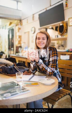 Portrait selbstbewusste junge Studentin, die Kaffee trinkt und im Café studiert Stockfoto