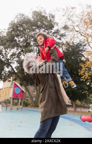 Großmutter hebt Enkelin auf dem Spielplatz Stockfoto