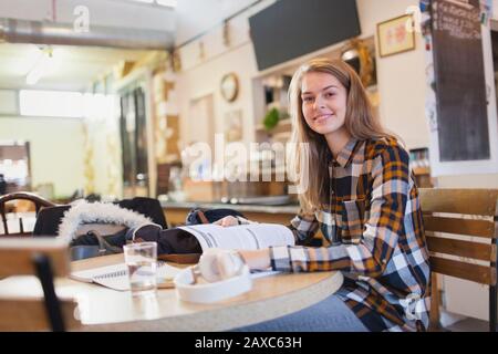 Portrait selbstbewusste junge Studentin im College, die am Café-Tisch studiert Stockfoto