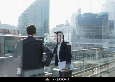 Geschäftsleute sprechen auf einem sonnigen, städtischen Balkon, Shoredisch, London Stockfoto