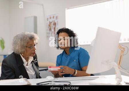 Hausärztin verschreibt in der Arztpraxis Medikamente an Oberpatientin Stockfoto