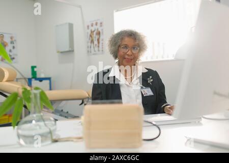 Portrait Oberarzt, der am Computer in der Arztpraxis arbeitet Stockfoto