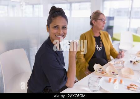 Portrait lächelnd, selbstbewusste Geschäftsfrau, die Sushi-Mittagessen genießt Stockfoto