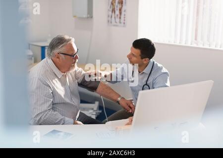 Männlicher Arzt überprüft den Blutdruck des leitenden Patienten in der Arztpraxis Stockfoto
