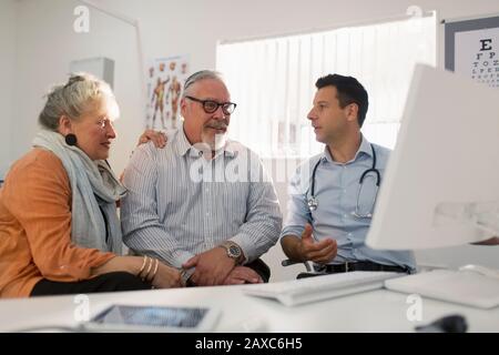 Arztbesprechung mit dem Senioren-Paar am Computer im Arztbüro Stockfoto