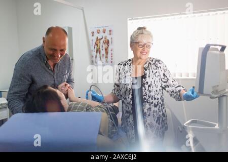 Techniker, der Ultraschall für schwangere Paare im Untersuchungsraum durchführt Stockfoto