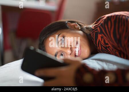 Lächelndes, glückliches Mädchen im Teenager-Alter mit Smartphone Stockfoto
