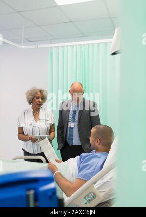 Ärzte runden machen, im Gespräch mit Patient im Krankenhaus Zimmer Stockfoto