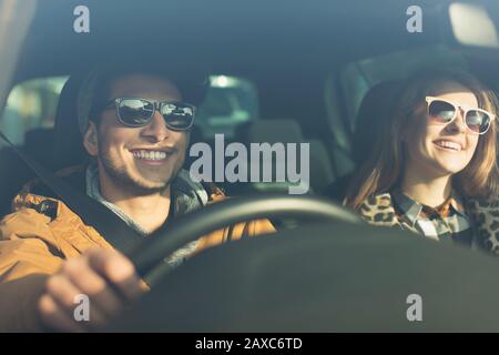 Glückliches junges Paar trägt Sonnenbrille im Auto Stockfoto