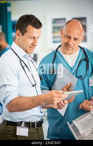 Ärzte beraten und verwenden digitale Tabletts im Krankenhaus Stockfoto