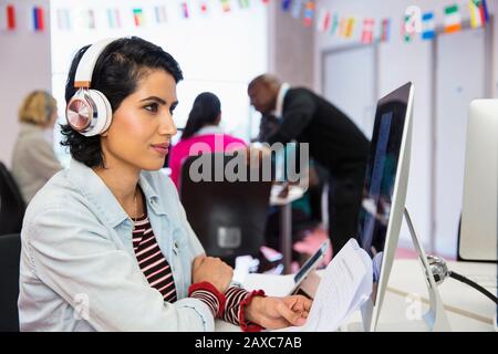 Studenten der Community mit Schwerpunkt und Kopfhörern, die Computer im Klassenzimmer verwenden Stockfoto