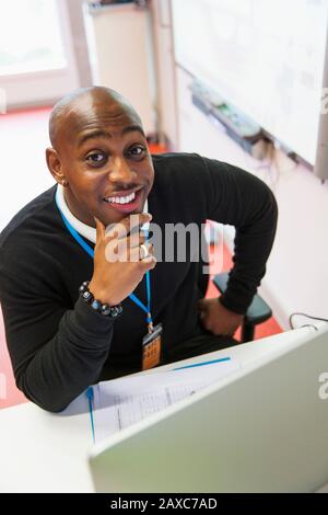 Portrait selbstbewusster, lächelnder, männlicher Community College-Lehrer am Computer im Klassenzimmer Stockfoto