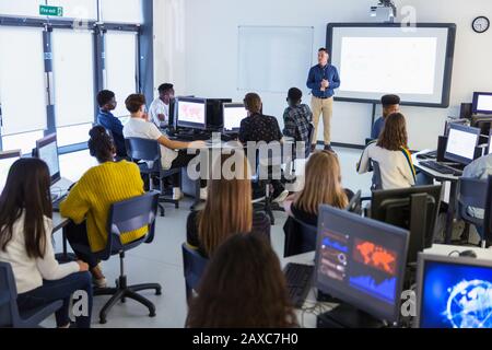 Schüler von jungen Schülern an Computern, die Lehrer auf der Projektionsleinwand im Klassenzimmer beobachten Stockfoto