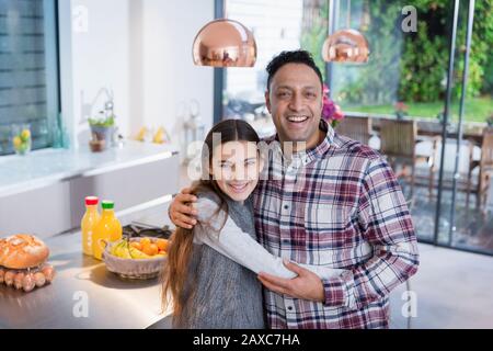 Portrait glücklicher Vater und Tochter umarmen sich in der Küche Stockfoto
