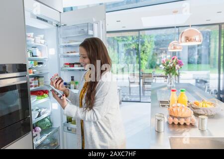 Frau mit digitaler Tablette im Kühlschrank in der Küche Stockfoto