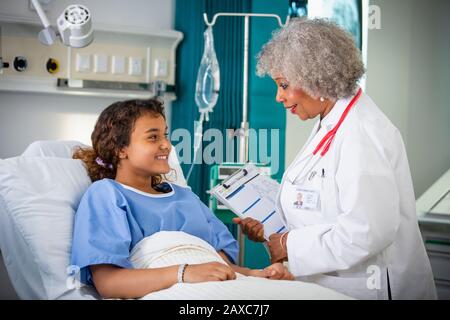 Ärztin spricht mit Mädchen-Patientin im Krankenhauszimmer Stockfoto