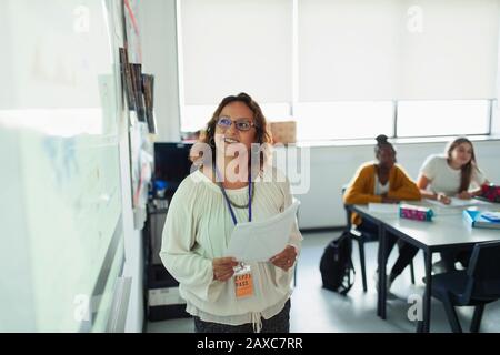 Lächelnder Lehrer, der die Lektion auf der Projektionsleinwand im Klassenzimmer führt Stockfoto