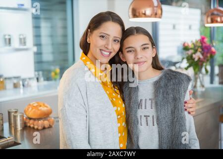 Portrait fröhliche Mutter und Tochter umarmen sich in der Küche Stockfoto