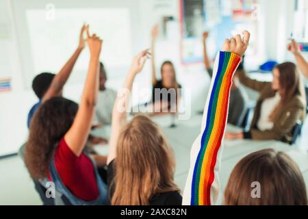 Highschool-Schüler mit aufgeworfenen Armen, die Fragen im Klassenzimmer stellen Stockfoto