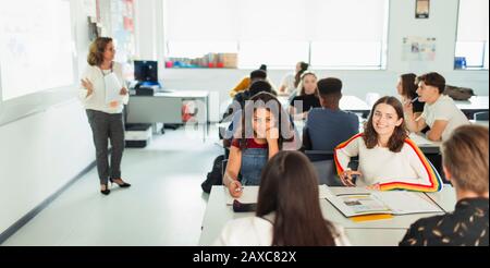 Schüler der High-School-Mädchen, die während des Unterrichts am Tisch im Klassenzimmer sprechen Stockfoto