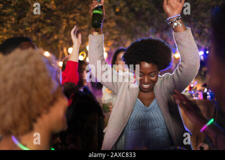 Unbeschwerte Frau, die auf der Gartenparty tanzt und trinkt Stockfoto