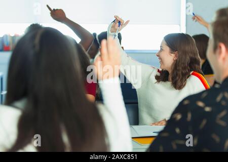 Schüler der High School mit erhobenen Händen im Klassenzimmer Stockfoto