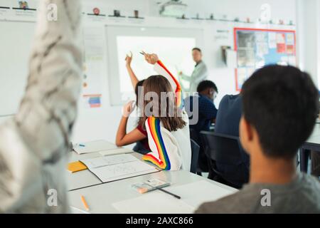 Schüler der High School mit erhobenen Händen während des Unterrichts im Klassenzimmer Stockfoto