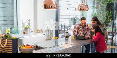 Vater und Töchter verwenden digitale Tablette in der Morgenküche Stockfoto