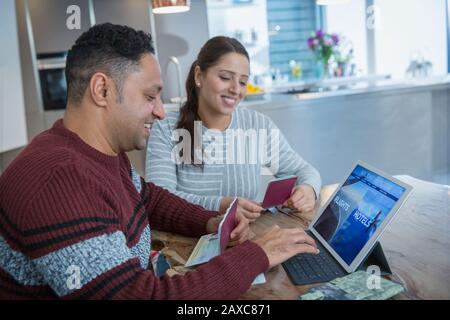 Glückliches Paar mit Reisepässen, die Urlaub auf dem digitalen Tablet planen Stockfoto