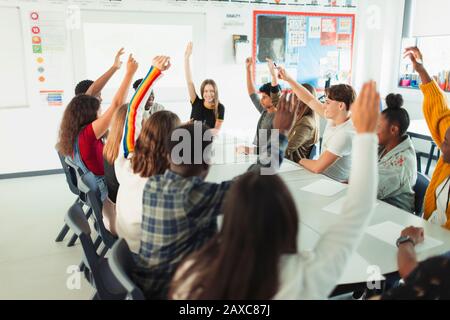 Schüler der High School mit Händen, die in der Debattierklasse aufgezogen wurden Stockfoto