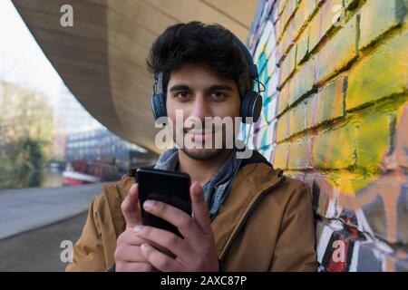 Portrait selbstbewusster junger Mann, der mit Kopfhörern und mp3-Player Musik hört Stockfoto