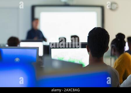 Schüler mit hohem Schüler und Studenten, die Computer verwenden und Lehrer im Klassenzimmer hören Stockfoto