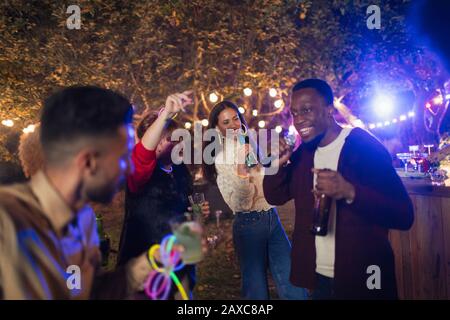 Freunde tanzen und singen Karaoke auf der Gartenparty Stockfoto