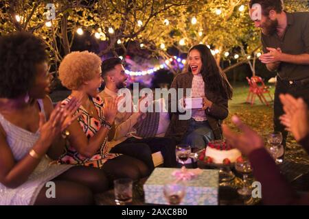 Freunde überraschende Frau mit Geschenk auf Gartengeburtstag Party Stockfoto