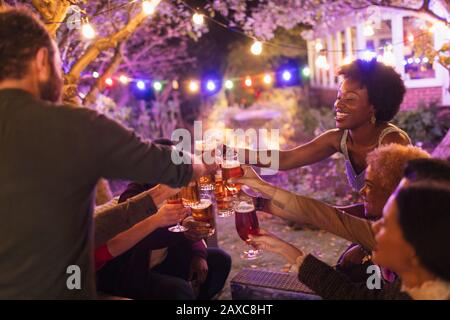 Fröhliche Freunde, die auf der Gartenparty Biergläser toben Stockfoto