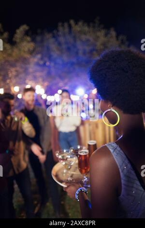 Junge Frau, die Cocktails auf der Gartenparty serviert Stockfoto