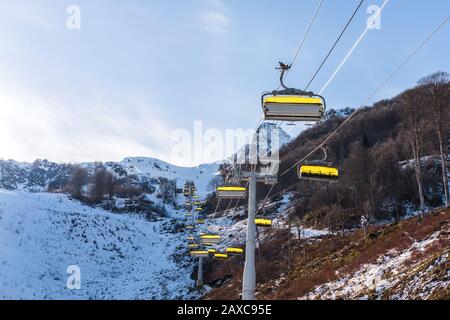 Skilift mit gelben Kabinen in einem Skigebiet in den Bergen gegen einen blauen Winterhimmel Stockfoto