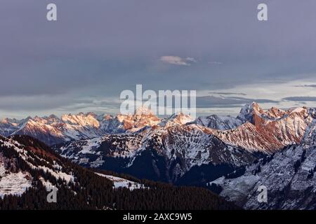 Sonnenuntergang über den Allgaeu-Alpen mit zwei dominierenden Gipfeln großer Widderstein und Hochkuenzelspitze - Blick vom Portlahorn-Gipfel in Österreich Stockfoto