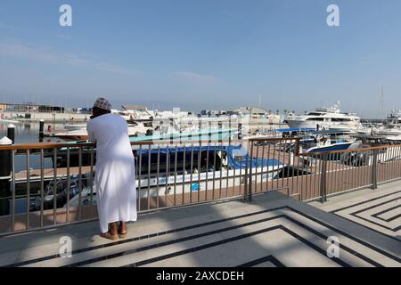 Muscat/Oman - 11. Februar 2020: Ein lokaler Mann blickt auf die Prahlerei in Al Mouj (The Wave) Marina in der omanischen Hauptstadt Muscat Stockfoto