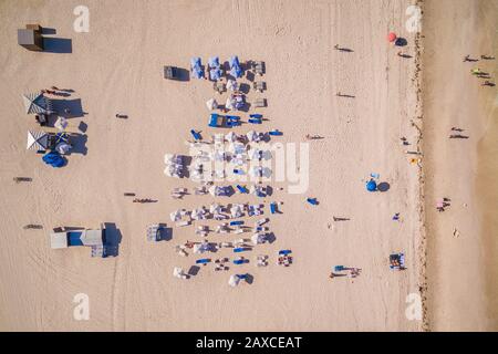 Top Down Luftbild der Strandsommerszene mit weißen Sonnenschirmen und zum Sonnenbaden in Miami, Florida, USA. Stockfoto