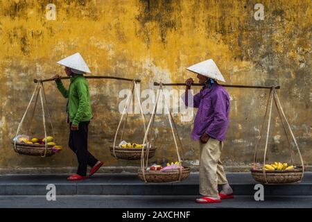 Vietnamesische Straßenhändler tragen traditionelle Strohhüte auf den Straßen von Hoi An Der Altstadt, Provinz Quang Nam, Vietnam. Stockfoto