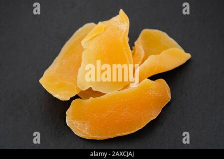 Draufsicht des Haufens von zergeschnittenem dehydriertem Mango auf schwarzem Hintergrund. Stücke trockener Mango. Obstgurken. Stockfoto
