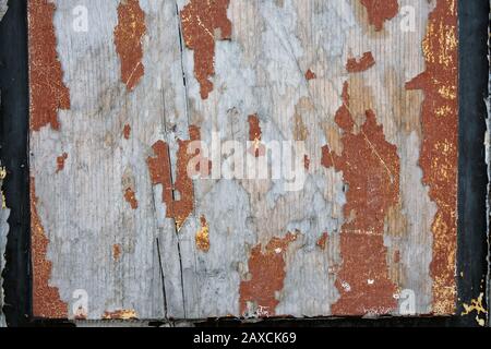 Fragment einer alten Holztür. Holzbrettstruktur mit schälender brauner Farbe. Altes verkratztes verblichenes Brett mit schwarz lackierten Kanten. Stockfoto