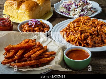 Veganer Grillplatz. Gebackene Bohnen im Südstaaten-Stil, Coleslaw, Brötchen zum Abendessen und Pommes frites. Stockfoto