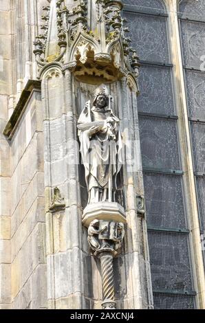 Detail der Außenfassade der St.-John-Kathedrale in Hertogenbosch, Nordbrabant, Niederlande. Holländische Gotik, größte katholische Kirche der Niederlande. Statue auf vertikalem Foto. Stockfoto