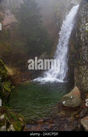 Der malerische Wasserfall, bekannt als Inferno Well, fällt in einen klaren grünen Pool in Serra da Estrela, Portugal Stockfoto