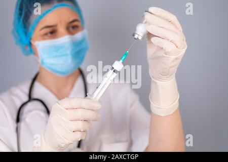 Die Hände des Arztes füllen die Spritze mit einem Impfstoff. Medizinisches Behandlungskonzept. Der Schwerpunkt liegt auf der Spritze. Stockfoto