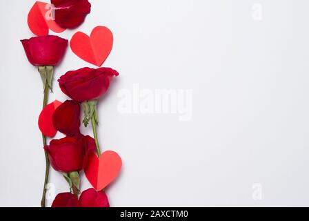 Rote Rosen und Papierherzen im Hintergrund Konzept der Liebe oder Valentinstag mit Kopierraum Stockfoto