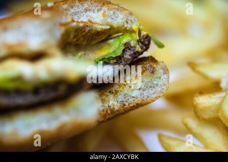 Nahaufnahme eines gebissenen Käseburgers. Food, Junk Food und Fast-Food-Konzept Stockfoto